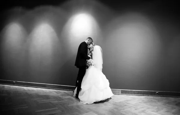 Newly married couple kissing against wall with projector lights