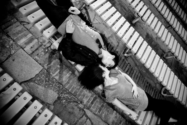 Portrait of couple lying face to face on bench and kissing