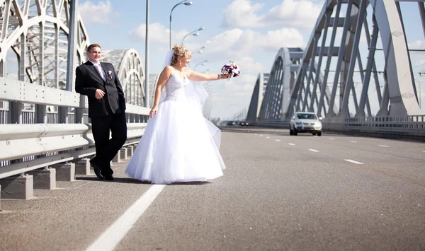 Newly married couple hitchhiking on road