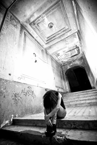 Depressed lonely woman sitting on stairs at abandoned building