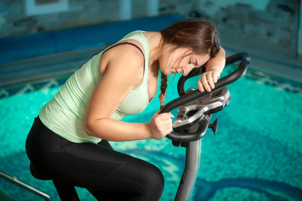 Brunette woman riding exercise bike at fitness club