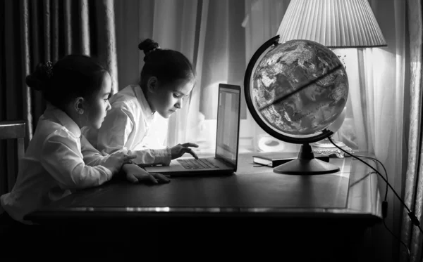 Portrait of two girls typing e-mail on laptop at night