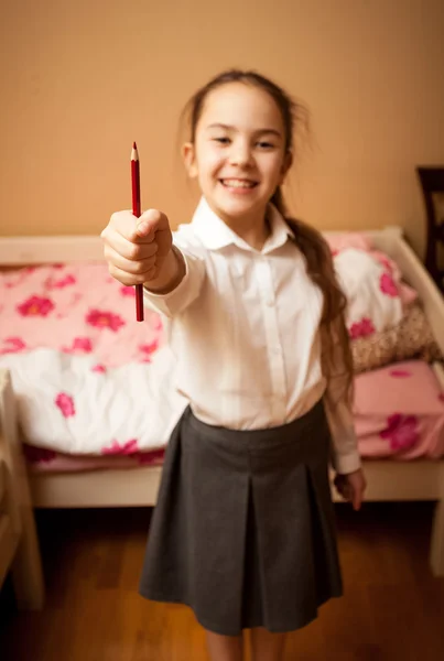 Portrait of smiling schoolgirl holding red pencil