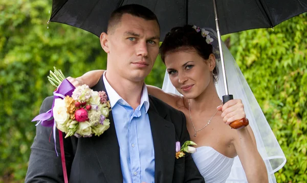 Just married couple hugging under umbrella