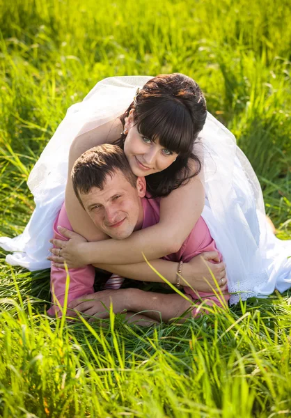 Portrait of happy bride lying on grooms back at field