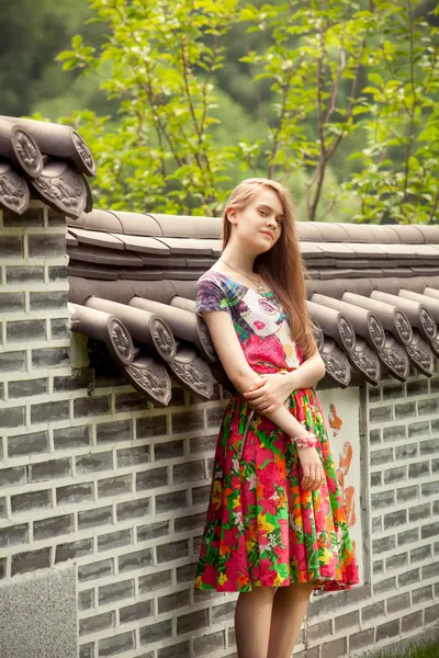 Young woman posing against ancient chinese wall