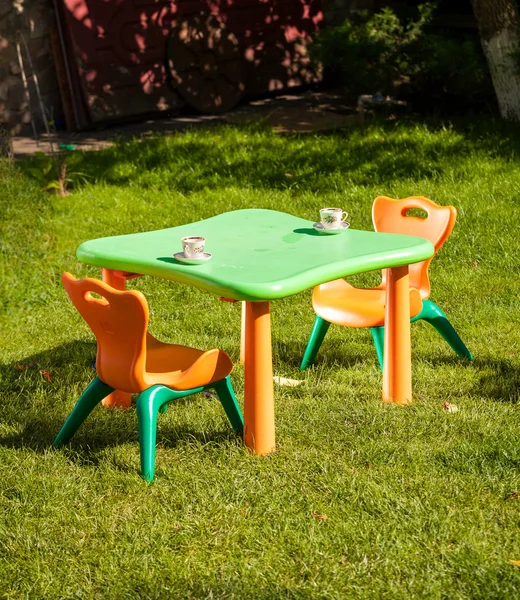 Toy plastic chair and table on grass at yard