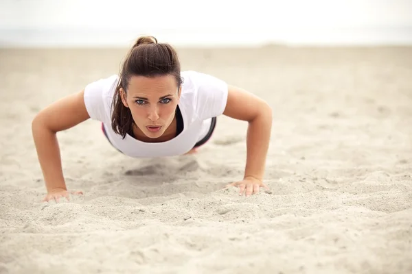 Athletic Woman Doing Push Up on the Beach