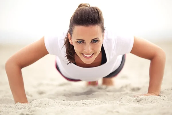 Woman on the Beach Smiling While Doing Push Up