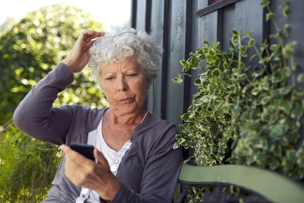 Elder woman reading text message on her cell phone