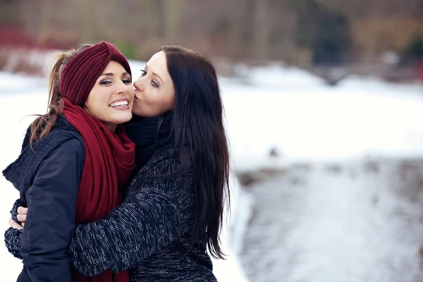 Attractive female kissing her friend on the cheek