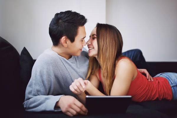 Romantic teenage couple on couch with tablet