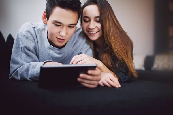 Relaxed teenage couple using digital tablet