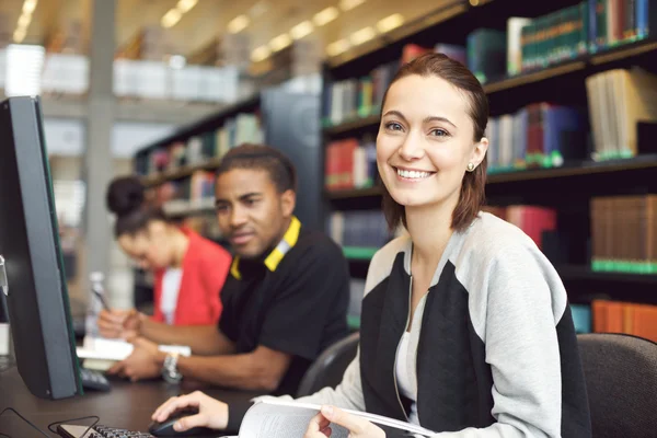 Beautiful young woman at library doing online research