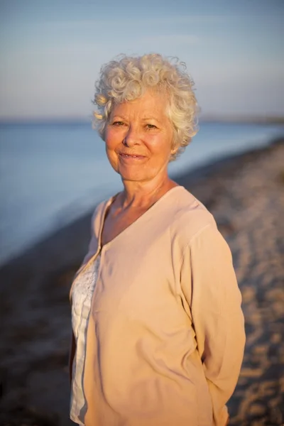 Beautiful old woman standing alone at the beach