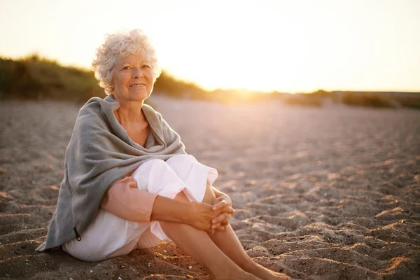 Retired woman sitting on the beach