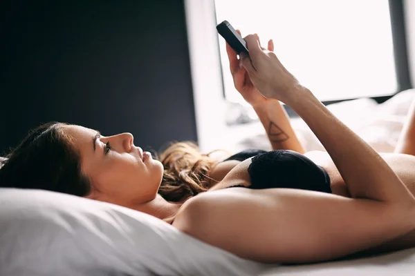 Female on bed reading text message on mobile phone