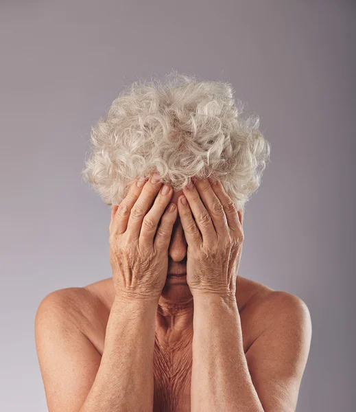 Sad senior woman covering her face