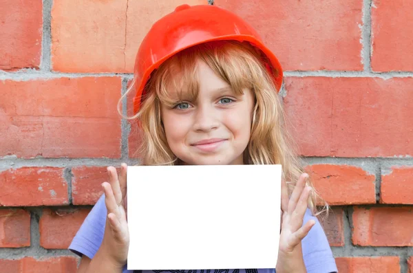 Little girl with helmet of construction worker and white blank card