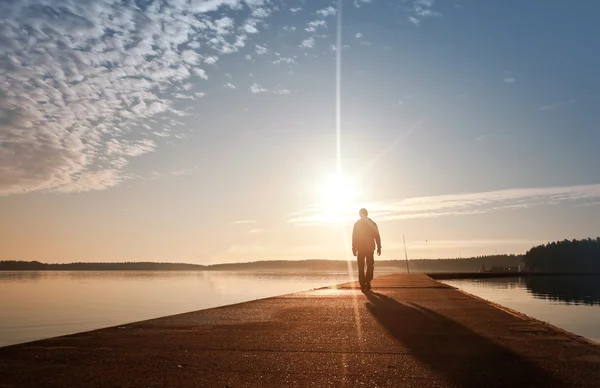 A man goes on the concrete pier in the sunrise