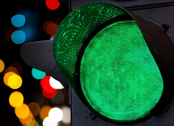 Green traffic light with colorful unfocused lights