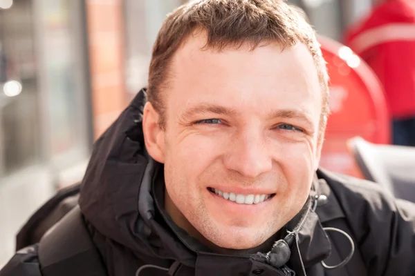 Close up city outdoor portrait of young smiling man in cold season