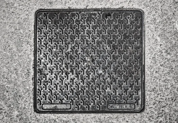 Square metal hatch on asphalt road