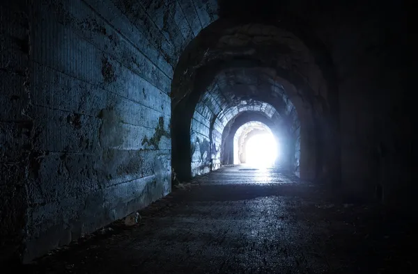 Blue glowing exit from dark abandoned tunnel