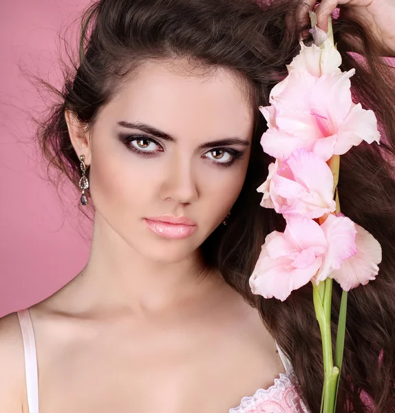 Young beautiful woman with white flower over pink