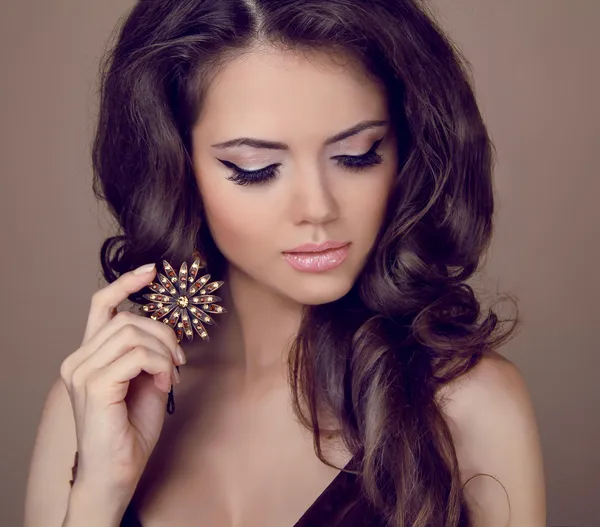 Beautiful woman with curly hair and evening make-up. Jewelry and