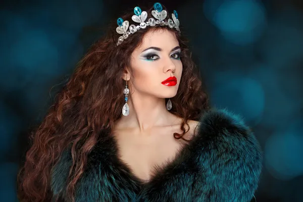 Beautiful woman with long hair in fur coat. Jewelry and Beauty.