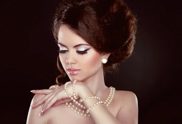 Beautiful pretty woman with pearls on her neck isolated on dark