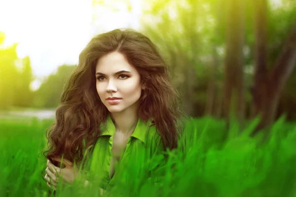 Teen girl resting over green field of grass, springtime. Nature