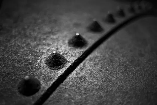 A black and white image of industrial rivets and rusty steel