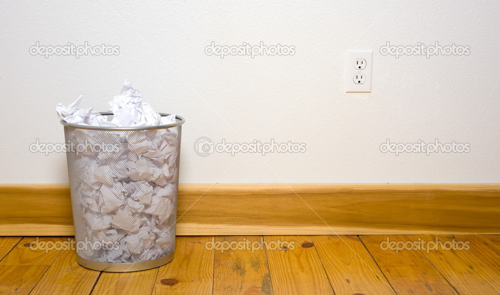 Office trash can on wood floor - Stock Image