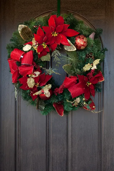 A red Christmas wreath on a wooden door