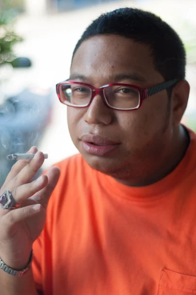 Asian man wearing glasses smoking cigarette