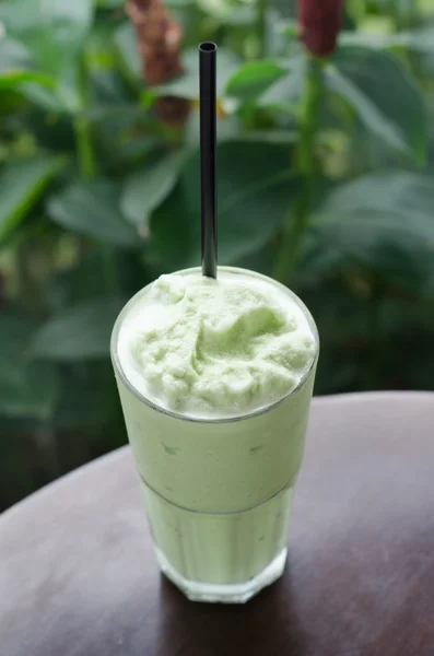 Green tea milk shake in glass on table