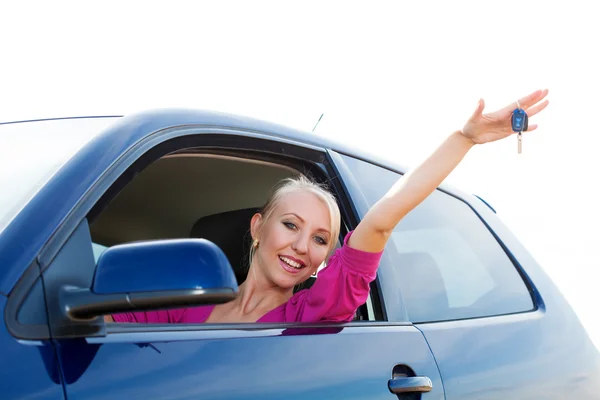 Happy car driver woman showing new car keys in car window