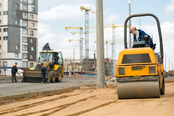 Road roller compacting sand during road works