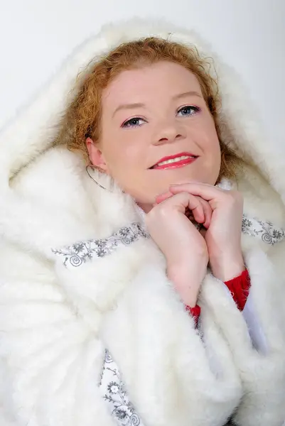 The young beautiful girl in a fur cap on a white background