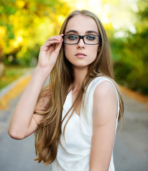 Attractive blonde woman wearing eyeglasses and white blouse at summer green park
