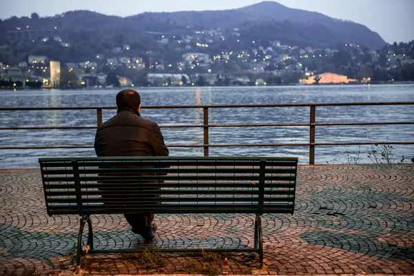 Lonely man sitting on the bench near the lake