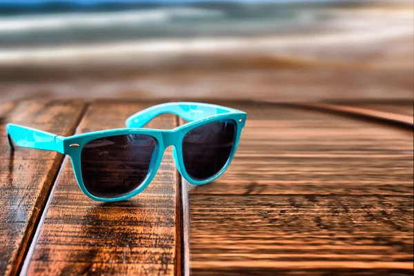 Sunglasses on wooden desk at the summer beach vacation