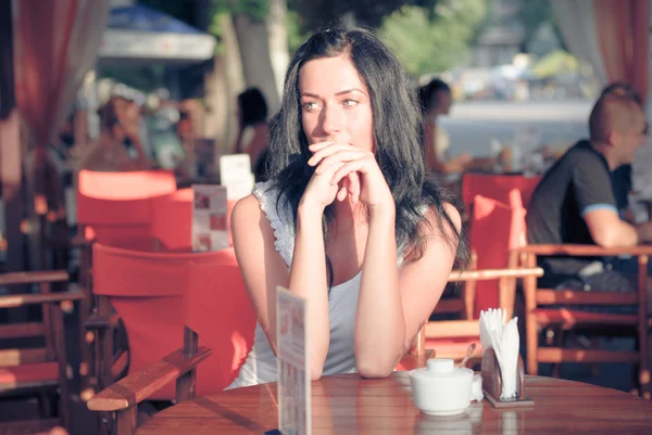 Young beautiful woman sitting on patio cafe and waiting