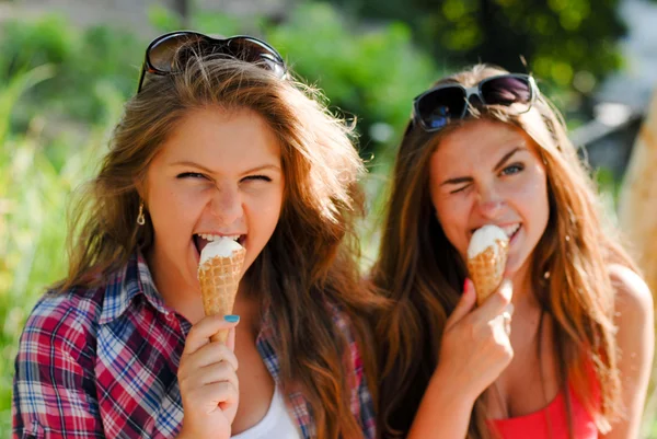 Two happy girl friends eating ice cream outdoors