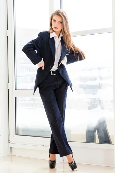 Young business woman wearing man's suit and high heels in office