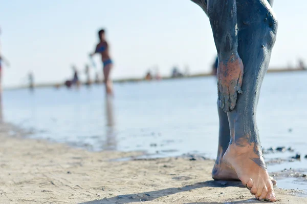 Woman applying mineral blue mud on legs at Sivash lake