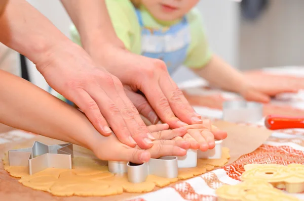 Close up little hands making the gingerbread cookies with mother help