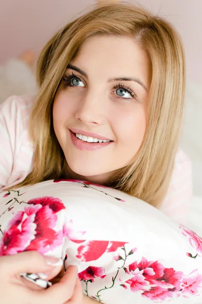 Woman lying on bed holding pillow